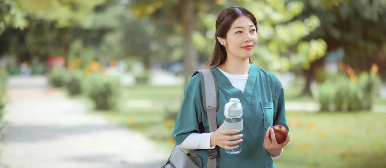 RN walking while holding her water bottle and apple