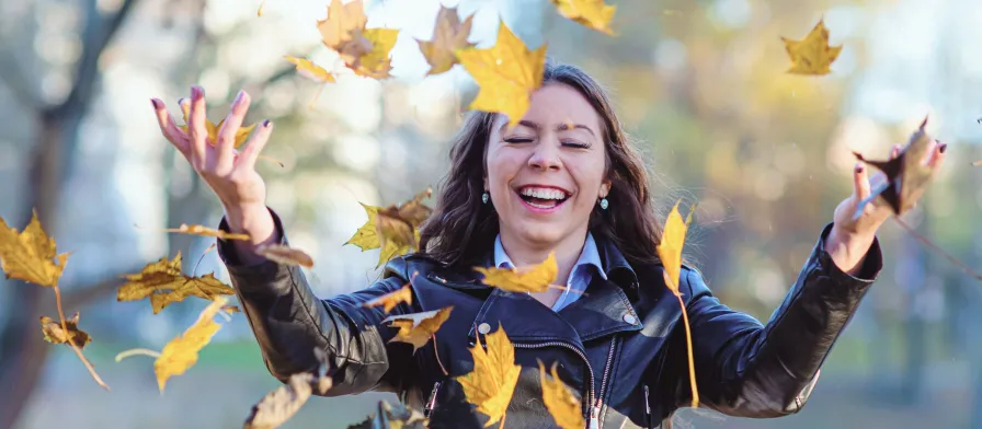 Attractive women tossing yellow leaves in the air while smiling